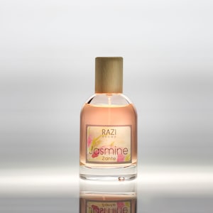 May include: A clear glass bottle with a wooden cap and a label that reads "Razi Aroma Jasmine Zante". The bottle is filled with a light pink liquid.