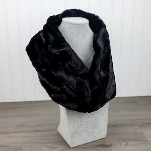 May include: A black faux fur infinity scarf. The scarf is soft and cozy, perfect for keeping warm in the winter.