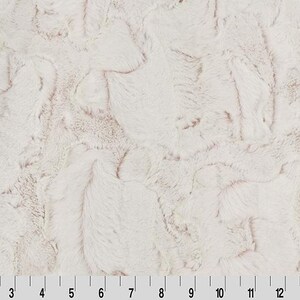 Puede incluir: Tela de piel sintética blanca con un sutil tono rosado. La tela tiene una textura suave y esponjosa.