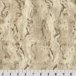 以下が含まれることがあります： 波打つようなテクスチャパターンが施されたベージュのフェイクファー生地。生地は柔らかく、豪華な感触です。