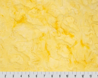 May include: Yellow faux fur fabric with a marbled pattern. The fabric is soft and fluffy.