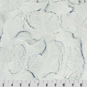 Puede incluir: Tela de piel sintética blanca con un patrón de remolino. La tela tiene una textura suave y mullida.