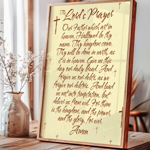 Puede incluir: Impresión enmarcada de la oración del Padre Nuestro, con elegante caligrafía. El texto en marrón cálido sobre un fondo crema, con pequeños acentos de cruz. El marco es de color marrón claro, agregando calidez a la obra religiosa.