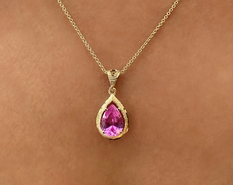 May include: A gold chain necklace with a pink pear-shaped gemstone pendant.