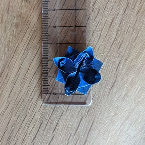 May include: A blue origami flower with the text "dannuim Ziehzeugs" on it.