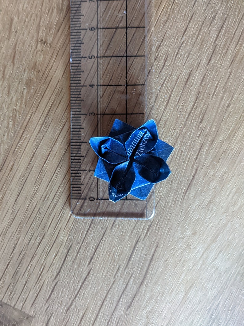 May include: A blue origami flower with the text "dannuim Ziehzeugs" on it.