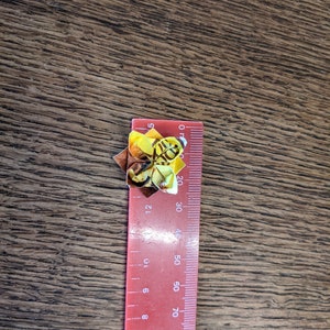May include: A red ruler with black markings, measuring up to 90 cm, with a yellow and brown origami bee on top.