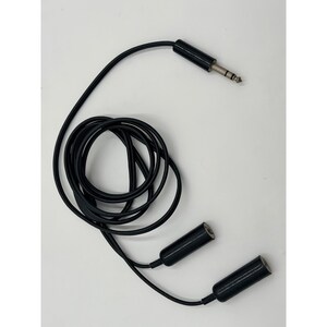 Puede incluir: Un cable divisor de audio en Y de color negro con un conector jack macho de 6,35 mm y dos conectores jack hembra de 6,35 mm. El cable est&aacute; enrollado en un bucle circular, con el conector macho en la parte superior y los dos extremos hembra abajo.