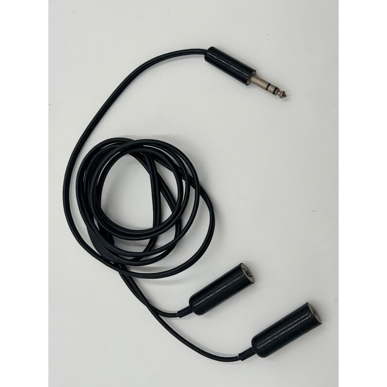 Puede incluir: Un cable divisor de audio en Y de color negro con un conector jack macho de 6,35 mm y dos conectores jack hembra de 6,35 mm. El cable est&aacute; enrollado en un bucle circular, con el conector macho en la parte superior y los dos extremos hembra abajo.