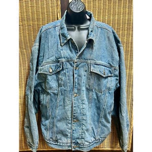 May include: A light blue denim jacket with two chest pockets and two side pockets. The jacket has a button-up front and a collared neckline. The jacket is displayed on a black mannequin.