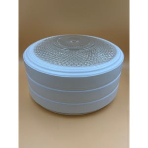 May include: A white and clear glass ceiling light fixture. The fixture has a round, layered design with a clear, textured glass center. The light fixture is a classic design.