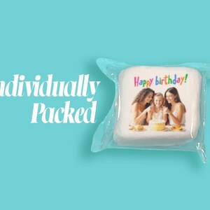 May include: A square, white item with a photo of three people around a cake, wrapped in clear plastic. The text "Happy birthday!" is written in colorful letters. The words "Individually Packed" are on the left side of the image, against a teal background.