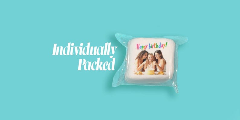 May include: A square, white item with a photo of three people around a cake, wrapped in clear plastic. The text "Happy birthday!" is written in colorful letters. The words "Individually Packed" are on the left side of the image, against a teal background.