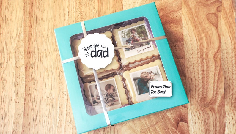May include: A turquoise gift box with a clear window showing four decorated cookies. Each cookie has a photo printed on it. One cookie has a white circle sticker with the text "Thank you! dad". Another cookie has a white rectangular sticker with the text "From: Tom To: Dad".