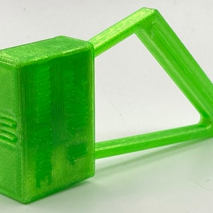 May include: A bright green plastic seal with a rectangular tag and a triangular loop. The tag has the text "SECURITY SEAL" printed on it.