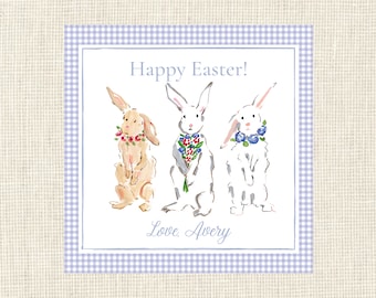 May include: A white card with a blue and white gingham border. The card has a watercolor illustration of three bunnies with flowers. The text "Happy Easter!" is at the top of the card and the text "Love, Avery" is at the bottom.
