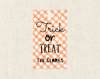 May include: A rectangular gift tag with an orange and white gingham pattern. The tag reads "Trick or Treat" in black script and block letters, with "The Clarks" below. A small hole is at the top.