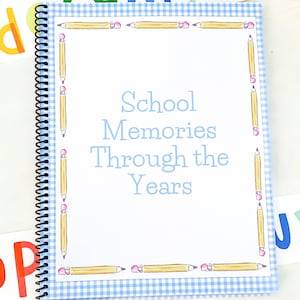 May include: A blue and white gingham scrapbook with a white border and a title that reads "School Memories Through the Years". The border is decorated with yellow pencils with pink erasers.