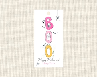 May include: A white Halloween gift tag with the word "BOO" in pink letters. The "O"s are decorated with a spider web and a pumpkin. A ghost, bats, and a spider are also featured. The tag reads "Happy Halloween!" and "Mary Kate".