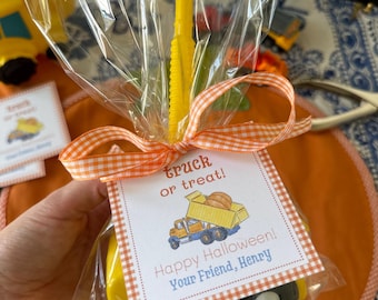 May include: A yellow toy truck in cellophane, tied with an orange and white gingham ribbon. The tag says "truck or treat!" with a truck graphic and "Happy Halloween! Your Friend, Henry."