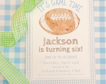Puede incluir: Un fondo a cuadros azul claro y blanco con una tarjeta blanca en la parte superior. La tarjeta tiene una ilustración de fútbol marrón con el texto "IT'S GAME TIME" en la parte superior. El texto "Jackson is turning six!" está debajo del fútbol. La tarjeta también incluye el texto "JOIN US TO CELEBRATE Saturday, April 24th 10:00 a.m. Jackson Country Club Wear your favorite team color or jersey!"