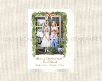 Könnte beinhalten: Eine Weihnachtskarte mit einem Familienfoto, umrahmt von einer grünen Aquarellgirlande und einer goldenen Schleife. Die Karte trägt die Aufschrift „MERRY CHRISTMAS!“ und enthält die Familiennamen. Der Hintergrund hat vertikale goldene Streifen.