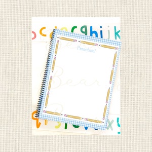 May include: A blue and white checkered notebook with a pencil border. The notebook says "Preschool" on the front. The notebook is on top of a sheet of paper with colorful letters.
