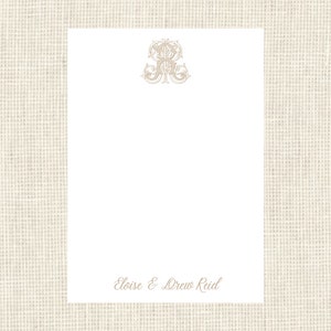 May include: White stationery card with a decorative monogram in the top center and the text "Eloise & Drew Reid" at the bottom center.