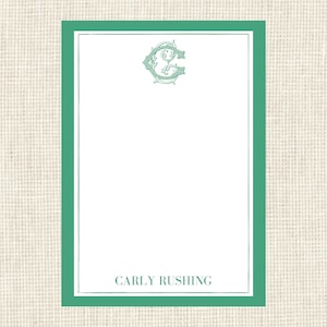 May include: A green border surrounds a white rectangle with a decorative letter "C" monogram at the top and the text "CARLY RUSHING" at the bottom.