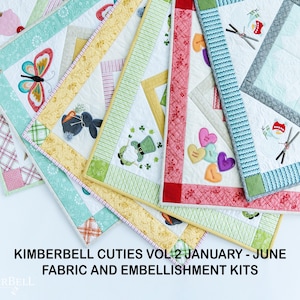 May include: A collection of fabric and embellishment kits for quilting. The kits feature a variety of designs, including butterflies, hearts, and shamrocks. The kits are labeled "Kimberbell Cuties Vol 2 January - June Fabric and Embellishment Kits".