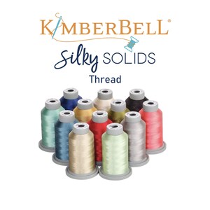 May include: A collection of 12 spools of thread in various colors, including red, blue, green, and gold. The thread is labeled "Kimberbell Silky Solids Thread".