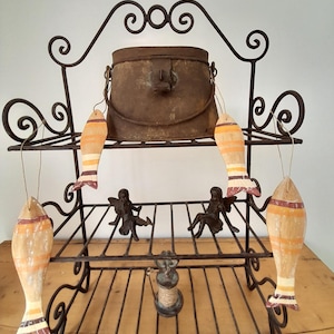 May include: A vintage-style wrought iron shelf unit, featuring a distressed metal pot and wooden fish decorations. The two-tiered shelf has scrollwork and small figurines. The overall design evokes a rustic, antique feel.