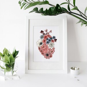 May include: A white framed print with a floral heart design. The heart is made up of pink, white, and blue flowers.