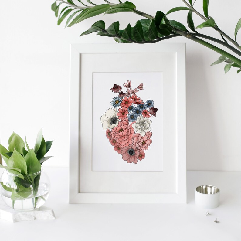 May include: A white framed print with a floral heart design. The heart is made up of pink, white, and blue flowers.