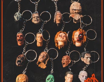 May include: A collection of horror-themed keychains featuring various monster and slasher movie characters. Each keychain has a detailed miniature head attached to a silver chain and ring. The word "HORROR" is visible in red.