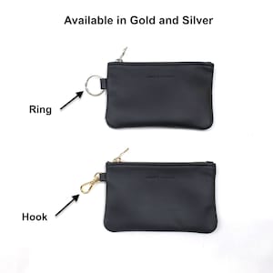 May include: Two black leather coin purses with zippers. The top purse has a silver ring attached to the zipper. The bottom purse has a gold hook attached to the zipper. Both purses have the text "Jessie & Company" embossed on the front.