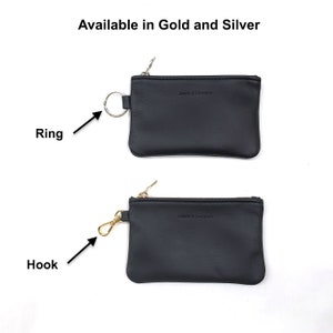 May include: Two black leather coin purses with zippers. The top purse has a silver ring attached to the zipper. The bottom purse has a gold hook attached to the zipper. Both purses have the text "Jessie & Company" embossed on the front.