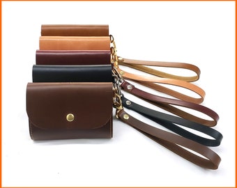 May include: Six leather wallets in different colors with a matching leather strap. The wallets are stacked on top of each other and the strap is looped around the top wallet.