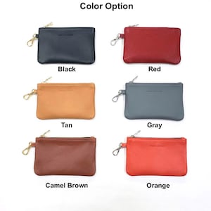 May include: Six leather coin purses with zipper closures and a metal ring. The purses are in the colors black, red, tan, gray, camel brown, and orange.