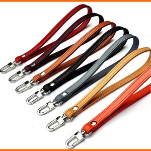 May include: Set of six leather wrist straps in various colors, including red, brown, black, gray, beige, and orange. Each strap has a silver metal hook.
