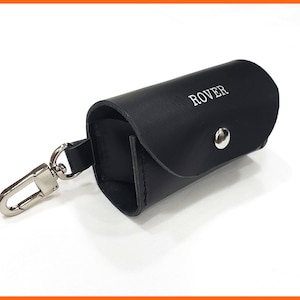 May include: A black leather key chain with a silver clasp and a small black leather pouch with the word "ROVER" embossed on it.