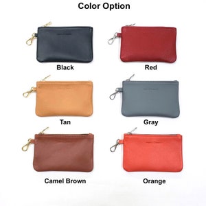 May include: Six leather coin purses with zipper closures and a metal ring. The purses are in the colors black, red, tan, gray, camel brown, and orange.