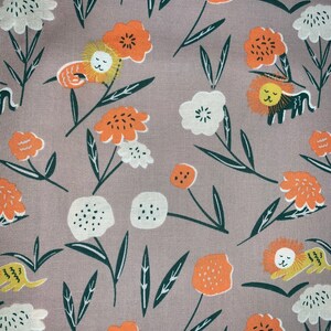 May include: A light brown fabric with a repeating pattern of orange and white flowers, green leaves, and yellow lions. The lions are sleeping and have closed eyes.