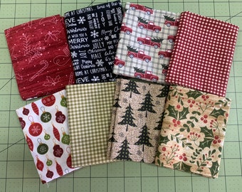 Pode incluir: Uma coleção de oito quadrados de tecido de Natal com vários padrões festivos, incluindo xadrez vermelho e branco, caminhão vermelho com árvores de Natal, xadrez verde e branco, enfeites vermelhos e brancos, árvores verdes e brancas e bagas de azevinho.