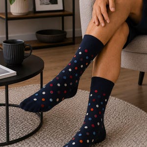 May include: A pair of navy blue crew socks featuring a repeating pattern of small, multicolored polka dots in shades of red, light blue, and white. The socks have a ribbed cuff at the top and extend to the mid-calf, covering the feet and lower legs.