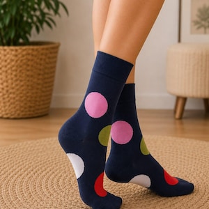 Könnte beinhalten: Ein Paar marineblaue Socken in Wadenlänge mit einem verstreuten Punktemuster in den Farben Rosa, Lindgrün, Weiß und Rot. Die Socken verfügen über ein geripptes Bündchen am oberen Rand und zeigen ein farbenfrohes Design auf dunklem Untergrund.