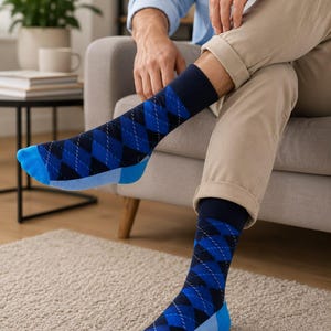 Könnte beinhalten: Ein Paar wadenlange Socken mit einem dunkelblau-schwarzen Argyle-Muster und feinen, sich kreuzenden weißen Linien. Die Socken haben einfarbige dunkelblaue Bündchen sowie leuchtend blaue Akzente an den Zehen und Fersen für einen starken Kontrast.