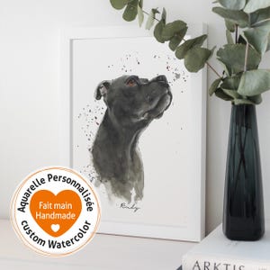 Puede incluir: Una pintura de acuarela de un perro negro con el nombre "Ruby" escrito debajo. La pintura está enmarcada en un marco blanco y tiene un fondo blanco con algunas salpicaduras de pintura. La pintura está rodeada por un borde blanco con el texto "Aquarelle Personnalisée Custom Watercolor Fait main Handmade" en un círculo.
