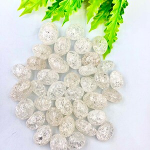 Puede incluir: Una colección de piedras de cuarzo transparente pulidas con una superficie texturizada y brillante. Las piedras tienen forma ovalada y tienen un aspecto natural y nublado.