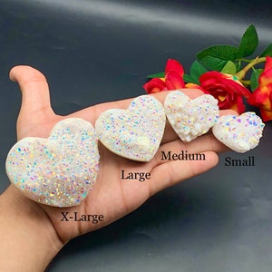 Puede incluir: Cuatro cúmulos de cristal blanco en forma de corazón de diferentes tamaños, etiquetados como "X-Large", "Large", "Medium" y "Small".